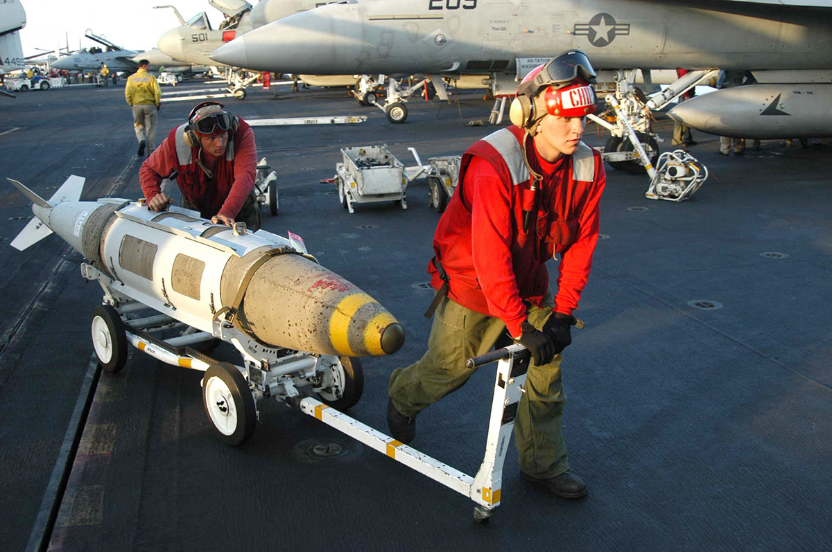 Артиллеристы перемещают Joint Direct Attack (JDAM) по полетной палубе авианосца