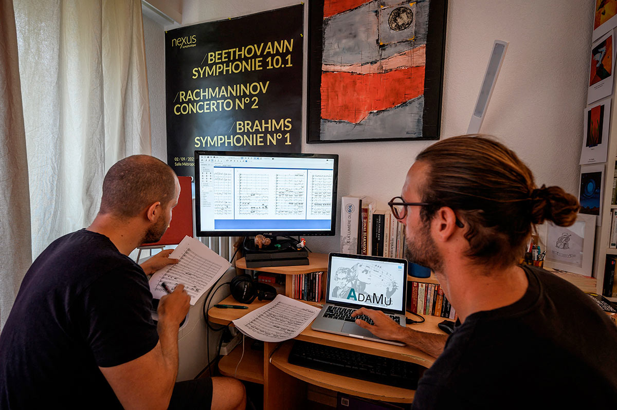 Программист ИИ и дирижер рассматривают партитуру симфонии Бетховена на экране компьютера