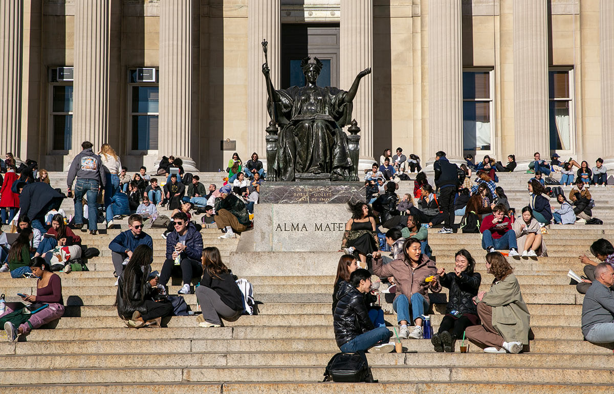 студенты отдыхают на ступенях Мемориальной библиотеки Лоу в кампусе Колумбийского университета в Нью-Йорке