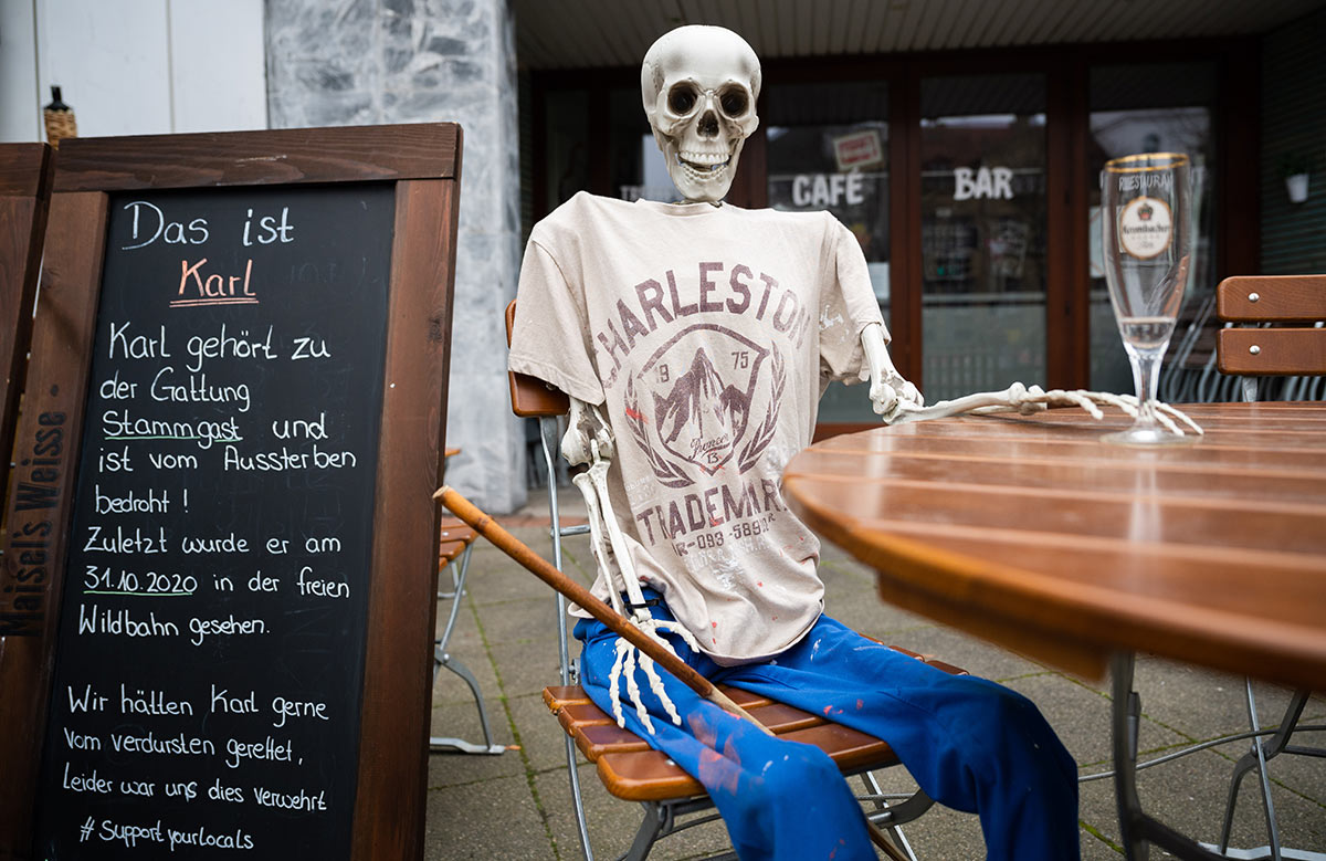 Скелет сидит с пустым пивным стаканом у ресторана, закрытого из-за пандемии коронавируса в Германии