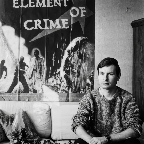 Режиссер Ларс Триер на фоне постера фильма «Элемент преступления».